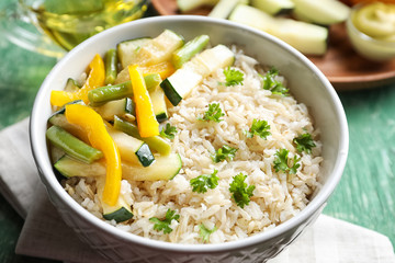Brown rice with vegetables in bowl on table, closeup