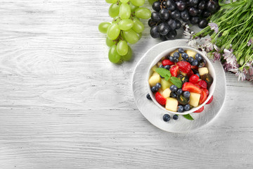 Bowl with delicious fruit salad on wooden table
