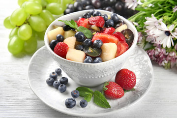Bowl with delicious fruit salad on wooden table