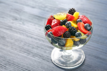 Dessert bowl with delicious fruit salad on wooden table