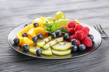 Plate with delicious fruit salad on wooden table