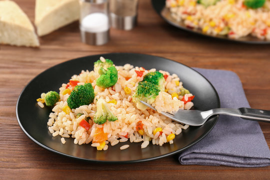 Plate with rice pilaf and broccoli on wooden table