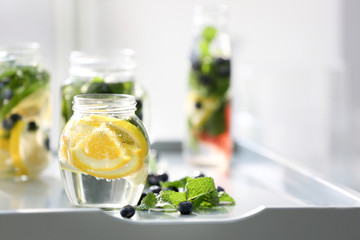 Glassware of infused water with fruits and berries on table