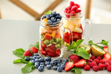 Mason jars with fruits and berries on table