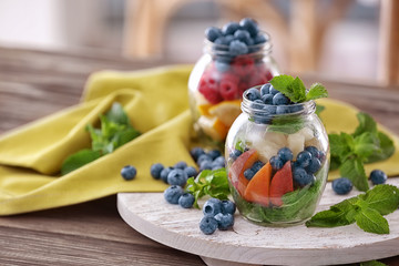 Jars with fruits and berries on wooden board
