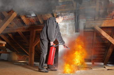 Mann beim Feuerlöschen im Dachboden mit Feuerlöscher
