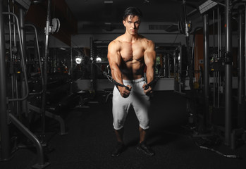 Naklejka na ściany i meble Young man training on exercise machine in gym