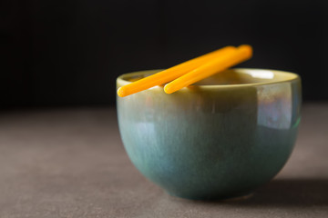 Obraz na płótnie Canvas Chinese food. Two chopsticks for eating. Food sticks. A bowl. Dark background.