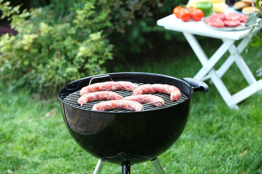 Barbecue grill with tasty sausages on backyard