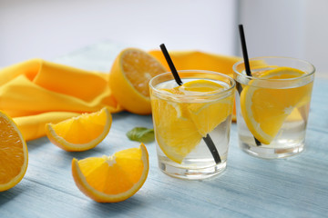 Glasses of delicious cocktails with orange on table