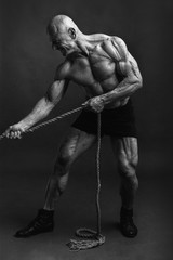 Fototapeta na wymiar Athletic man with great physique pulling rope and smiling. Black and white version