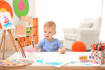 Little boy drawing at table indoors