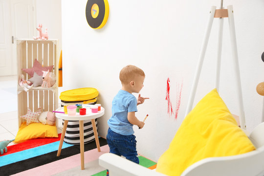 Little boy painting on wall at home