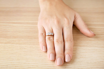 Woman's hand with beautiful engagement ring on table