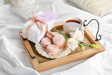 Wooden tray with breakfast and gift for Mother's day served in bed