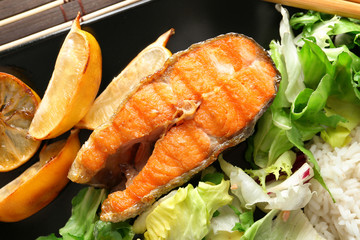Plate with tasty rainbow trout steak and garnish, closeup