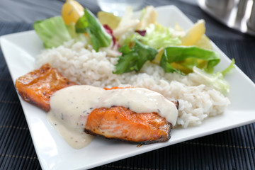 Tasty rainbow trout fillet with garnish and sauce on plate