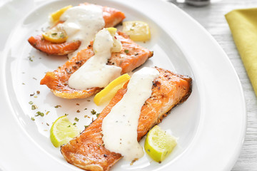 Tasty rainbow trout fillets with sauce on plate, closeup