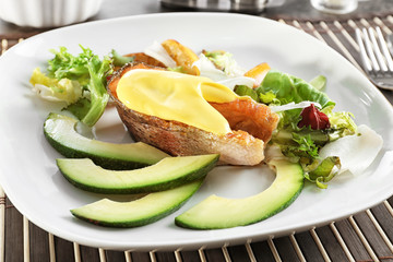 Tasty rainbow trout steak with garnish and sauce on plate, closeup