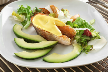 Tasty rainbow trout steak with garnish and sauce on plate, closeup