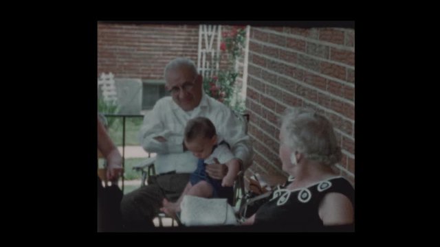 1960 Grandfather holds infant grandson on front porch