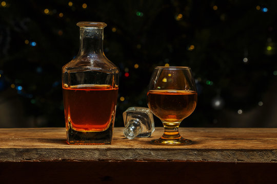 A glass of cognac or whiskey on a village table in the background of lights.