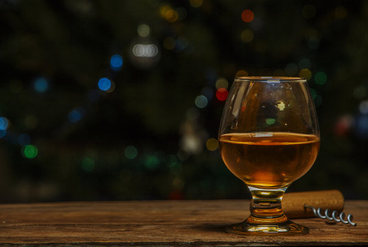 A glass of cognac or whiskey on a village table in the background of lights.