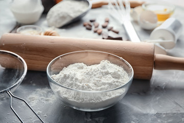Glass bowl with flour on grey table