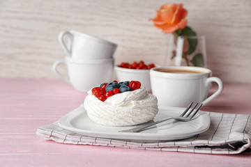 Plate with tasty Pavlova cake on table