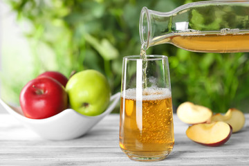 Pouring apple juice from bottle into glass on table