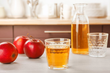 Glass of delicious apple juice on kitchen table