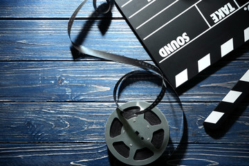 Movie clapper and reel on wooden background, top view