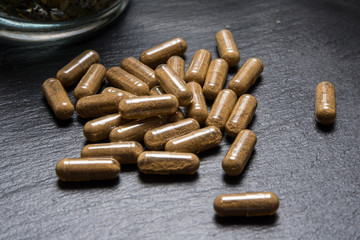 Herbal capsules on black stone background