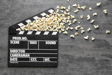 Movie clapper and popcorn on grey background, top view