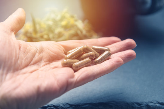 Herbal Capsules  In Woman Hand Black Stone Background