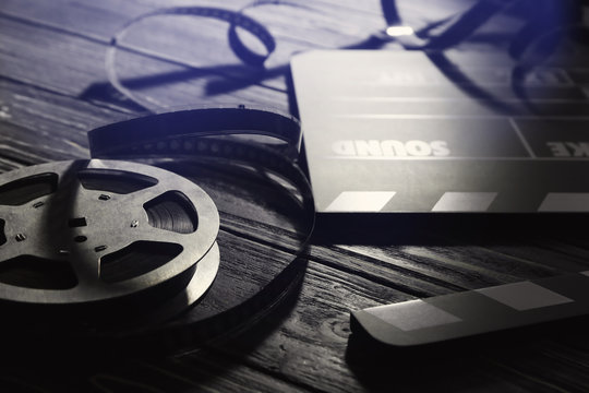 Movie clapper and reel on wooden background, closeup