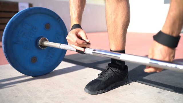 Weightlifting Deadlift wrist straps support for bodybuilding and powerlifting. Fitness man wearing accessory during barbell weight workout at gym. Closeup of hand and bar.