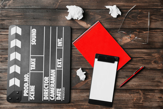 Composition with movie clapper, clipboard and notebook on wooden background, top view