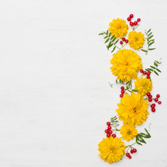 Top view on flowers composition on white wooden background. Frame made of wild flowers and berries