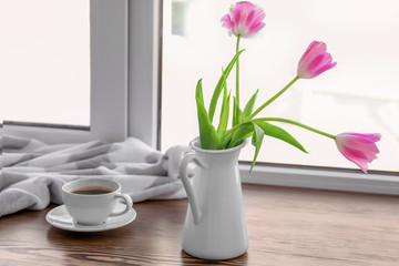 Cup of coffee with flowers on window sill