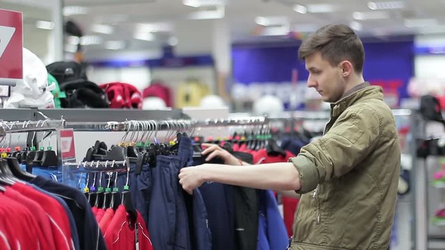 a young man choosing sports clothes in a shopping center