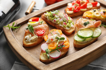 Wooden tray with tasty fresh bruschettas on table