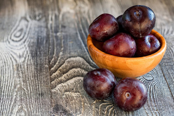 Obraz premium Garden plums in bowl on wooden table