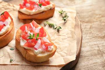Wooden board with tasty fresh bruschettas on table