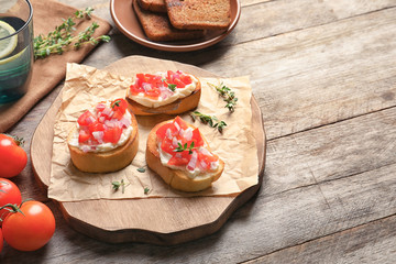 Wooden board with tasty fresh bruschettas on table
