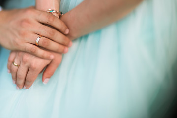 newlywed couple, groom and bride holding each other's hands with rings