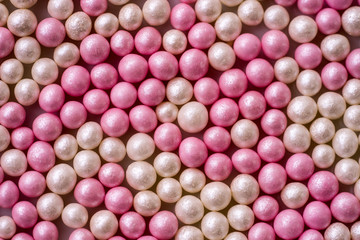 Closeup of one layer of pink and white sugar pearls (cake decor), from above