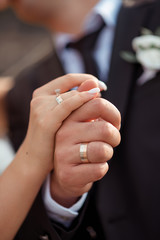 newlywed couple, groom and bride holding each other's hands with rings