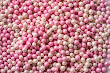 Closeup of a pile of pink and white sugar pearls (cake decor), from above