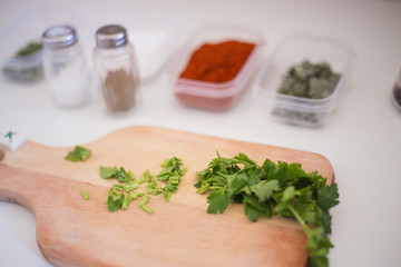 Green fresh parsley being prepared and cut for soup on the kitchen table and wooden cutting board with the seasonings aside salt and pepper for delicious meal food
